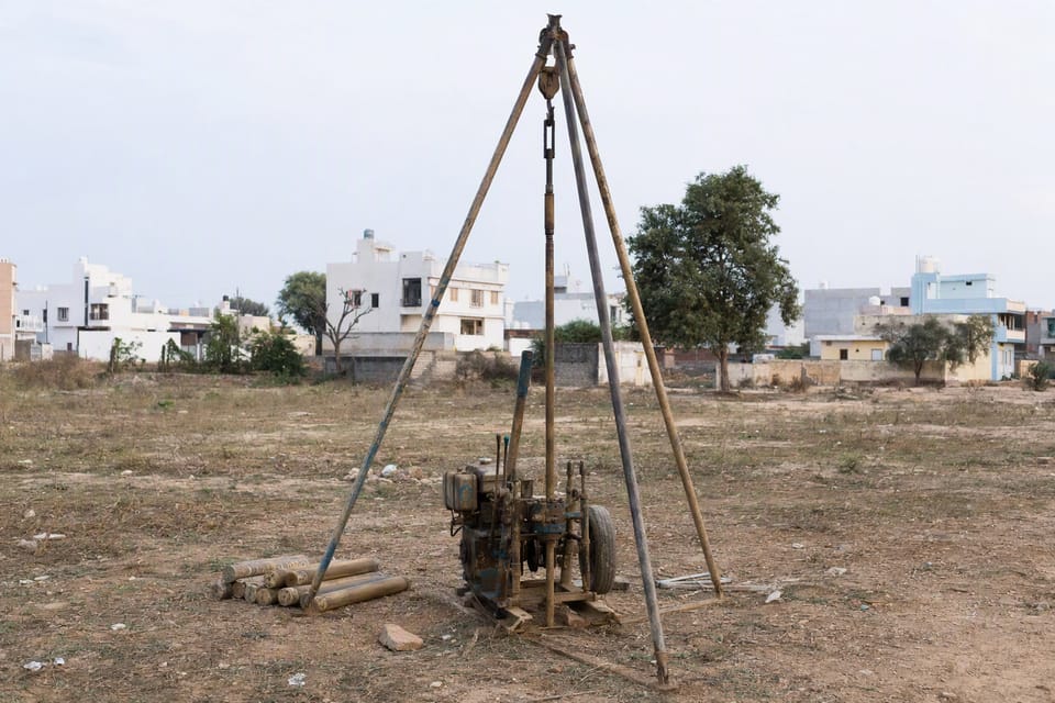 A small drilling rig set up on an empty plot for a soil investigation