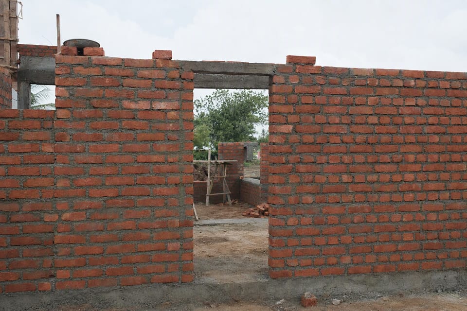 A partly built red brick wall with an empty door opening in it, seen from a wide angle