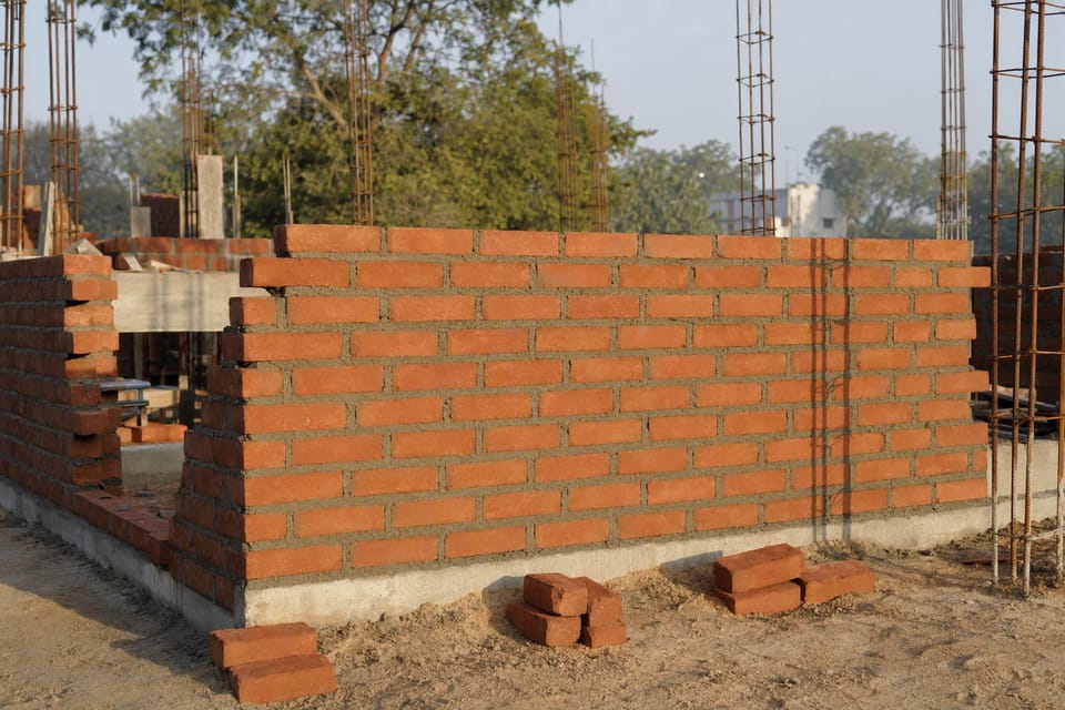 A half-built red brick wall with even mortar joints in soft light
