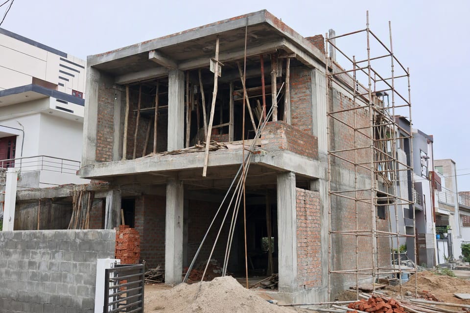 A two-storey house at the structure stage with scaffolding and brick walls going up