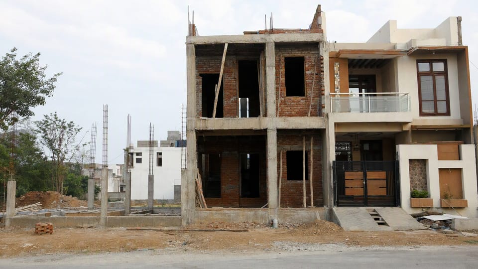 Three neighbouring house plots at different stages of construction, from foundation to nearly finished