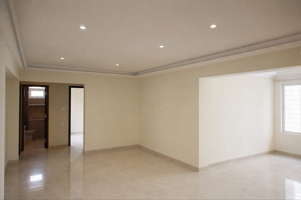 A finished room with a plain white ceiling, a simple edge and recessed lights