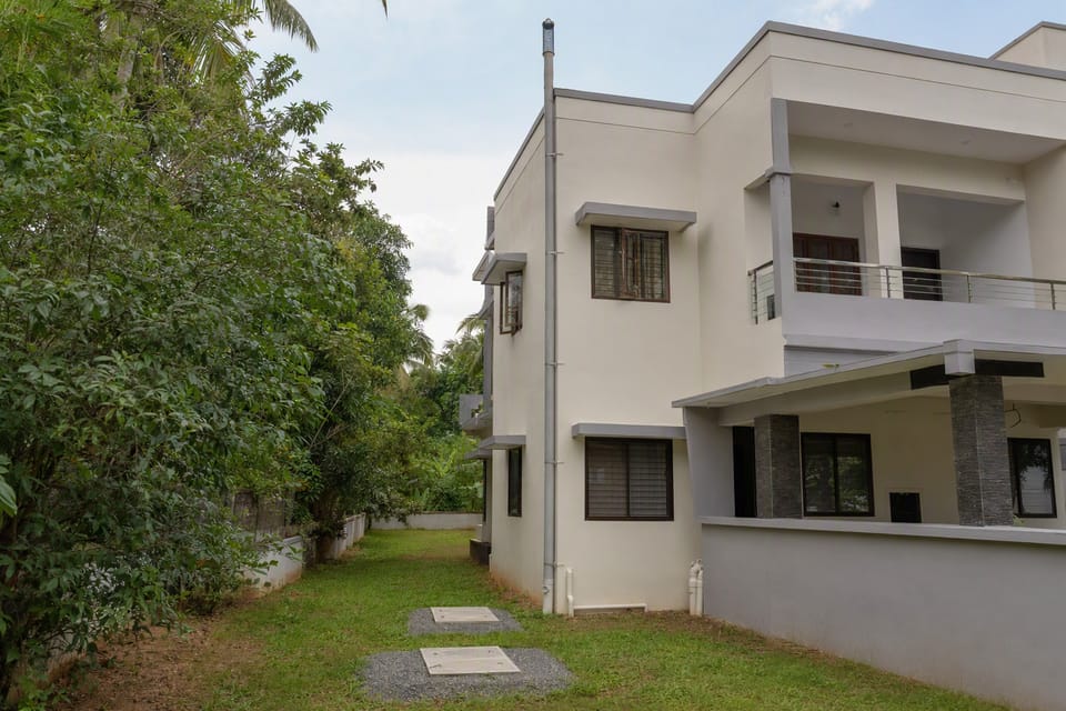 Two sealed concrete covers of a septic tank in a lawn beside a two-storey house, with a vent pipe running up the wall to above the roof