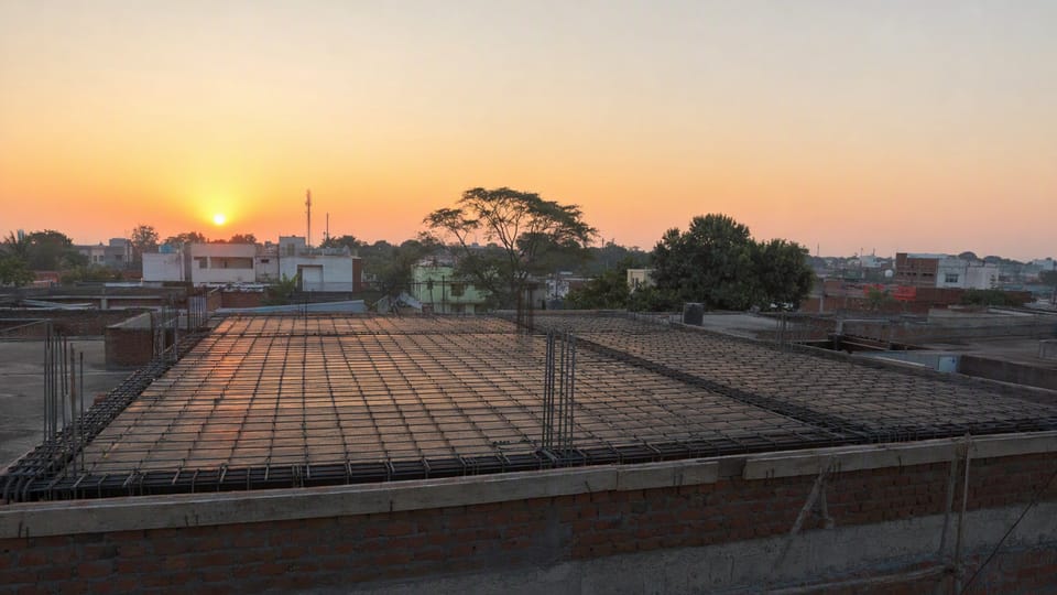 A house roof slab with a mesh of reinforcement bars laid ready for concreting, seen at sunrise