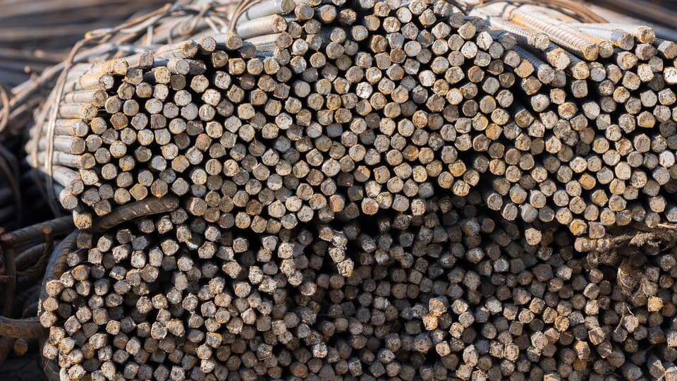 The cut ends of many tied ribbed steel reinforcement bars in a bundle in warm low sun at a building-material yard