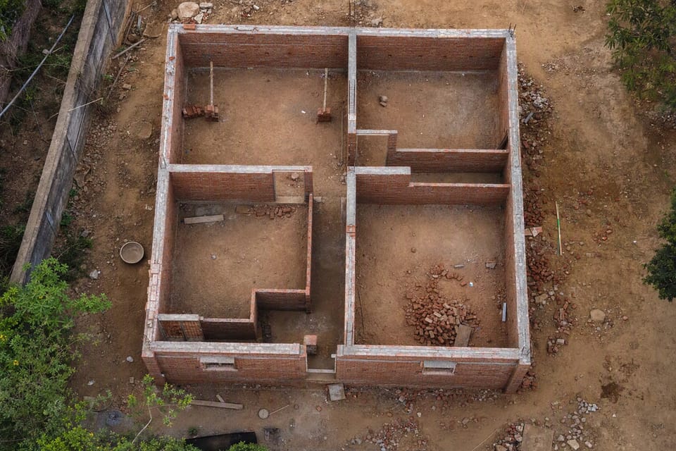 A top view of a roofless single-storey house under construction showing its outer and inner brick walls