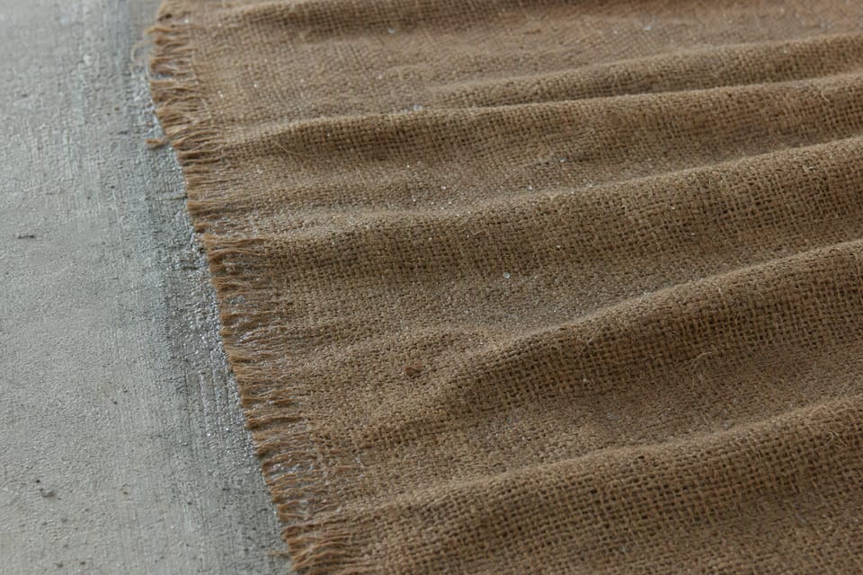 A damp hessian cloth laid over a grey concrete surface during curing